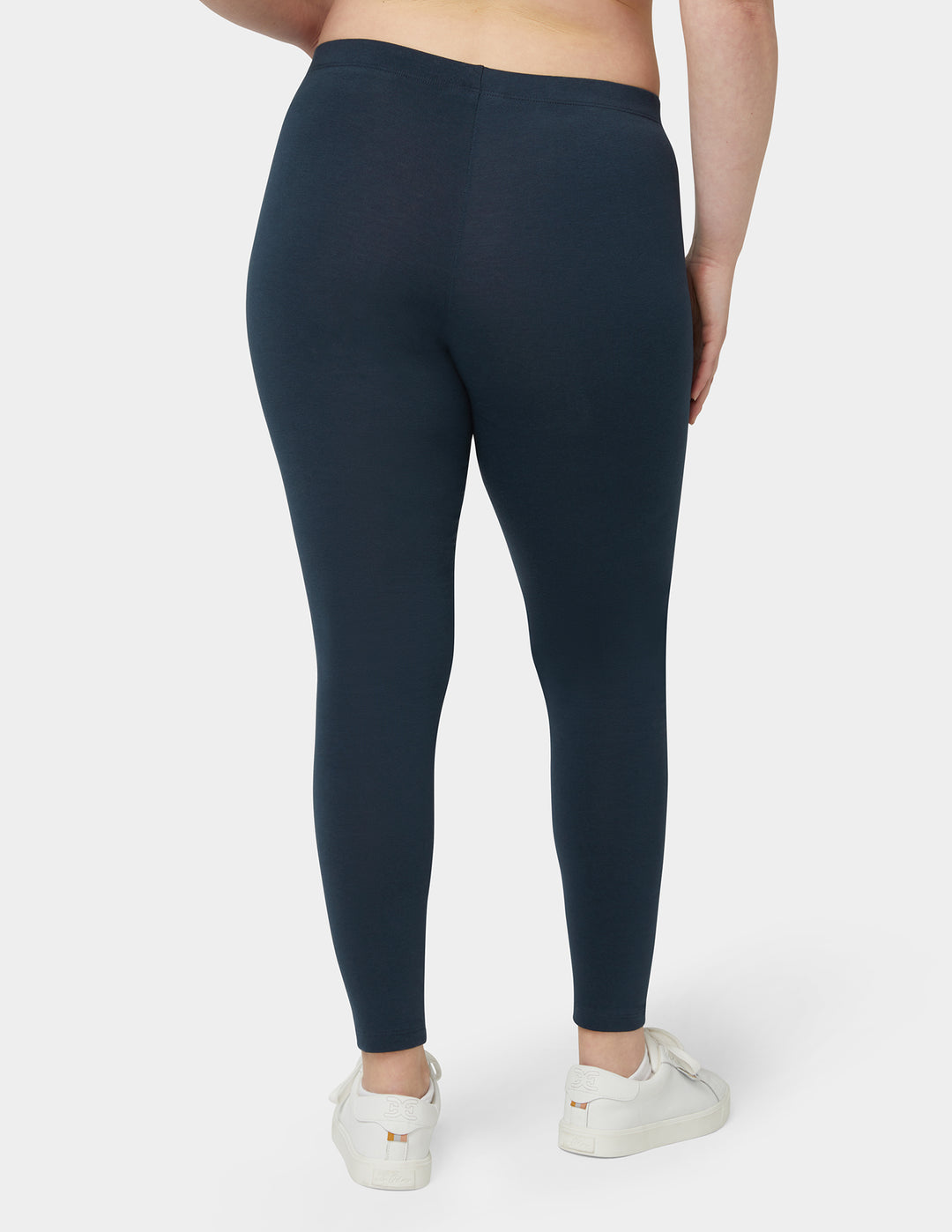 Person wearing dark blue leggings on a plain background