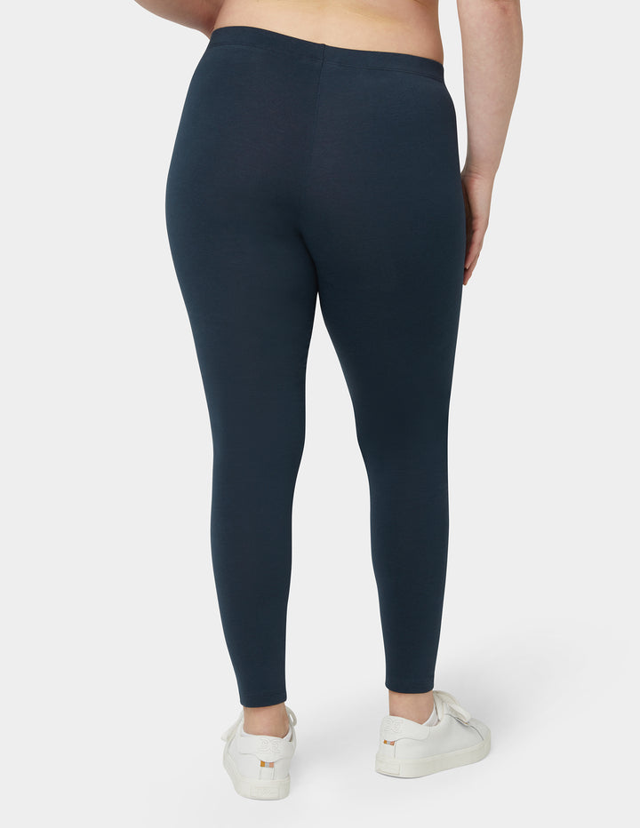 Person wearing dark blue leggings on a plain background
