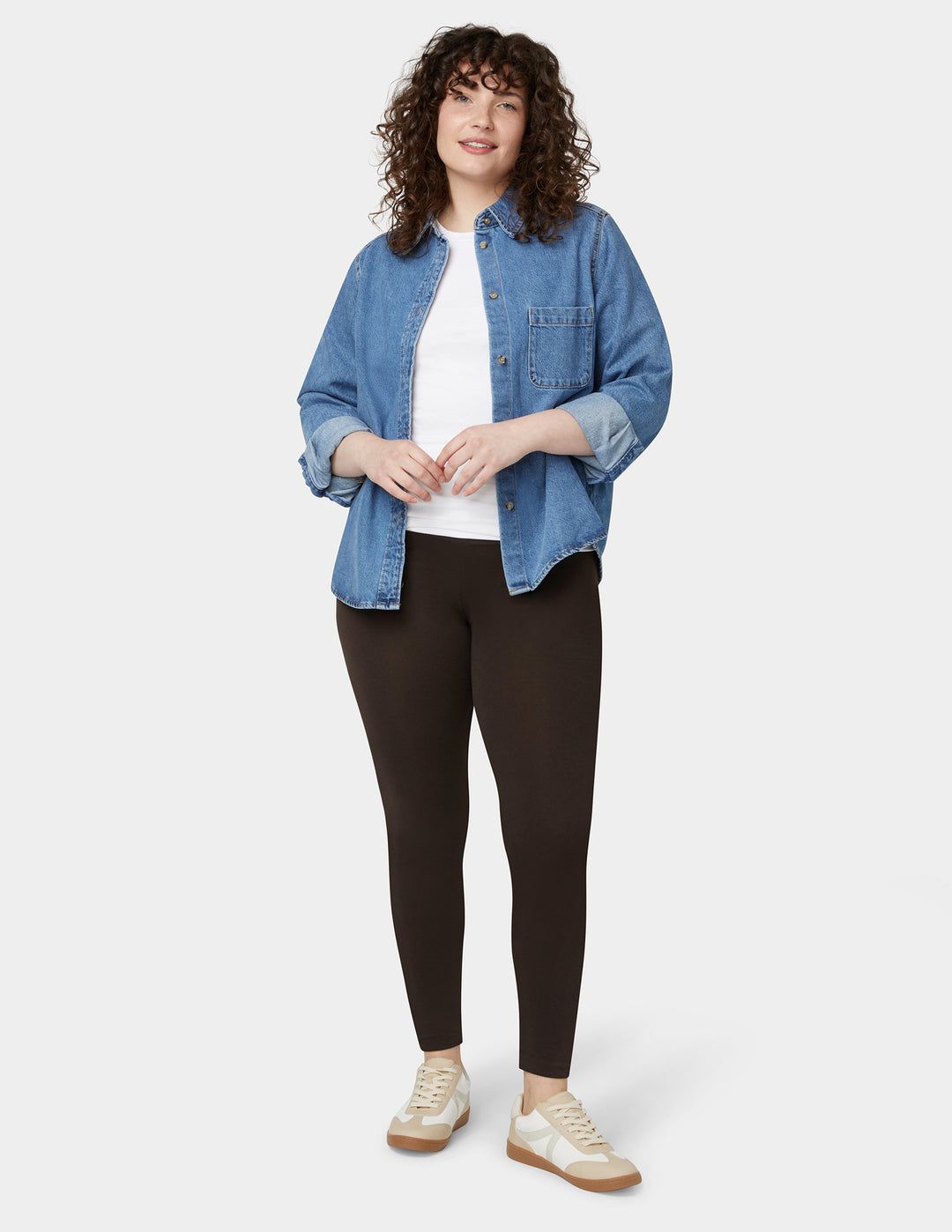 A model wearing brown cotton leggings with a white top and a blue denim jacket.