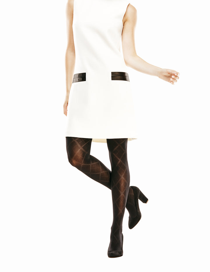 A person wearing a white dress and black control top tights with a diamond pattern design.