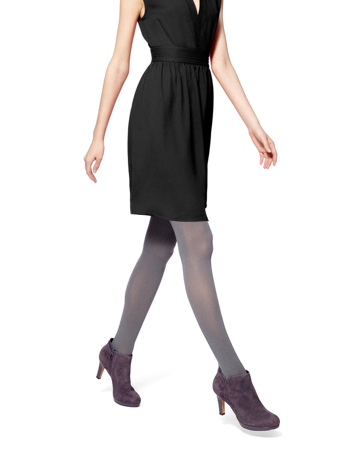 A person wearing a black dress and two-tone tights with a thin elastic waistband, paired with boots.