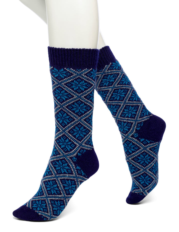 A pair of blue and white snowflake patterned outdoor socks worn on a white foot form.