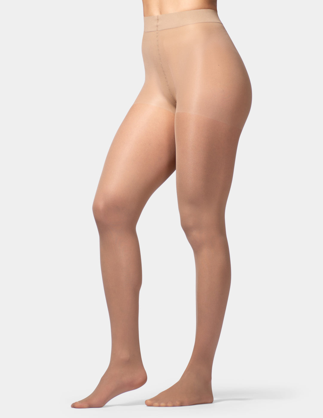 A side-profile view of a model's legs wearing sheer, high-waisted nude tights against a light gray studio background.
