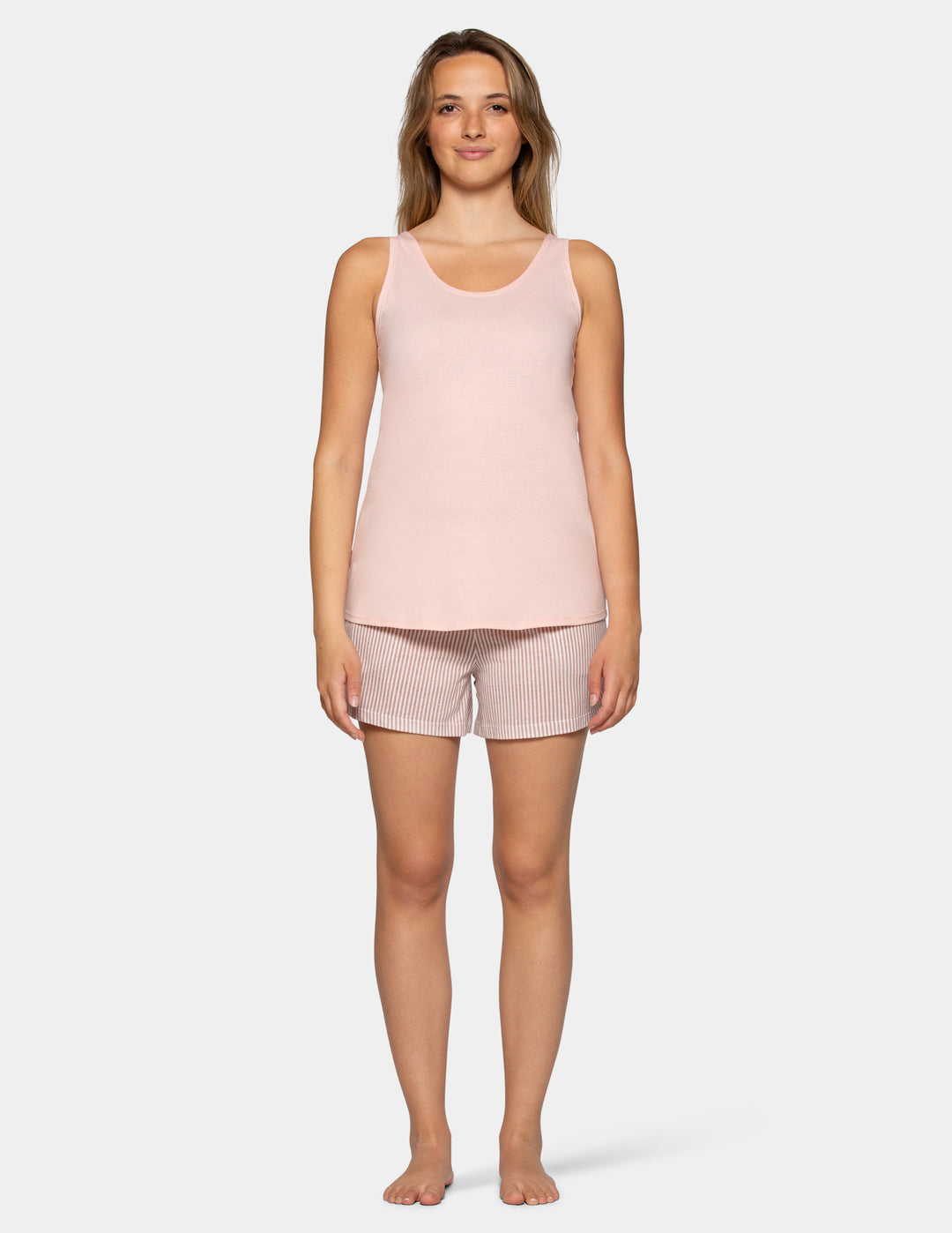 Woman wearing a light pink pajama tank top with stripe boxer shorts