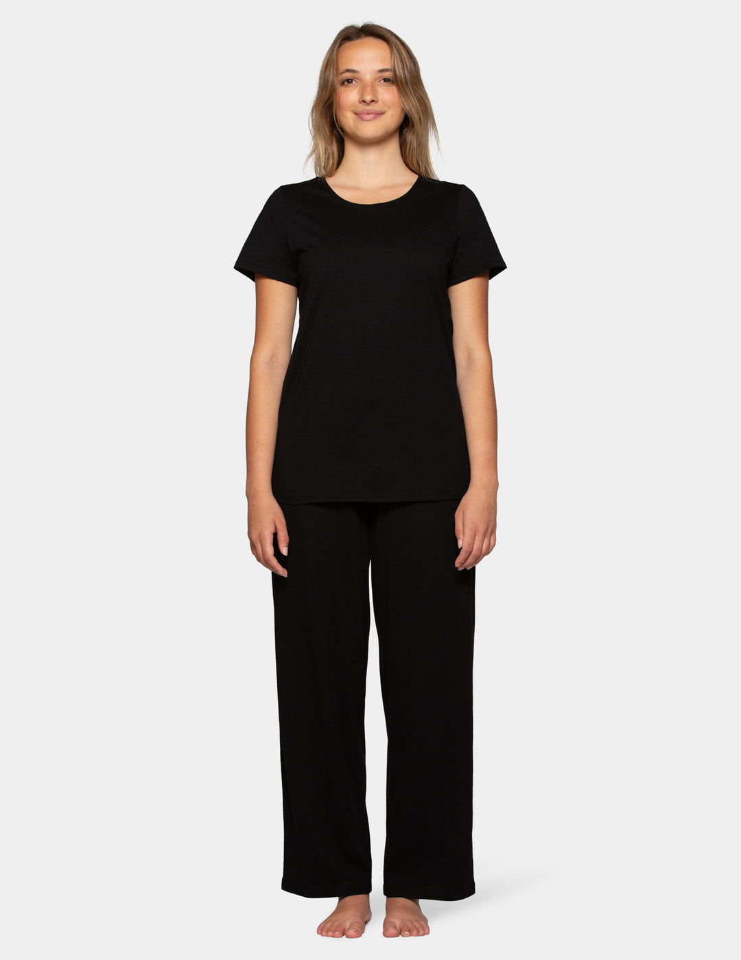 Woman wearing a black short sleeve pajama top and long pajama pants set