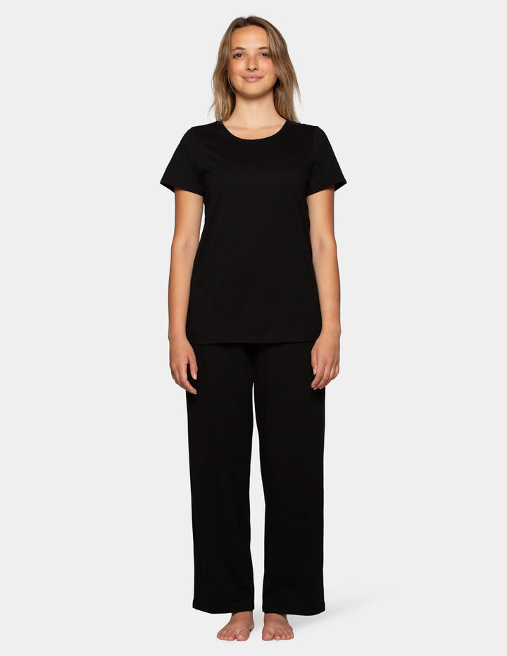 Woman wearing a black short sleeve pajama top and long pajama pants set