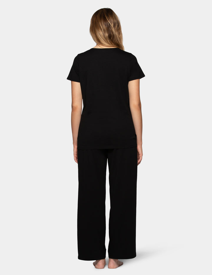 Woman wearing a black short sleeve pajama top and long pajama pants set