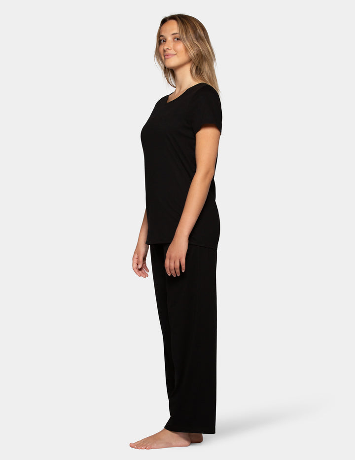 Woman wearing a black short sleeve pajama top and long pajama pants set sideview