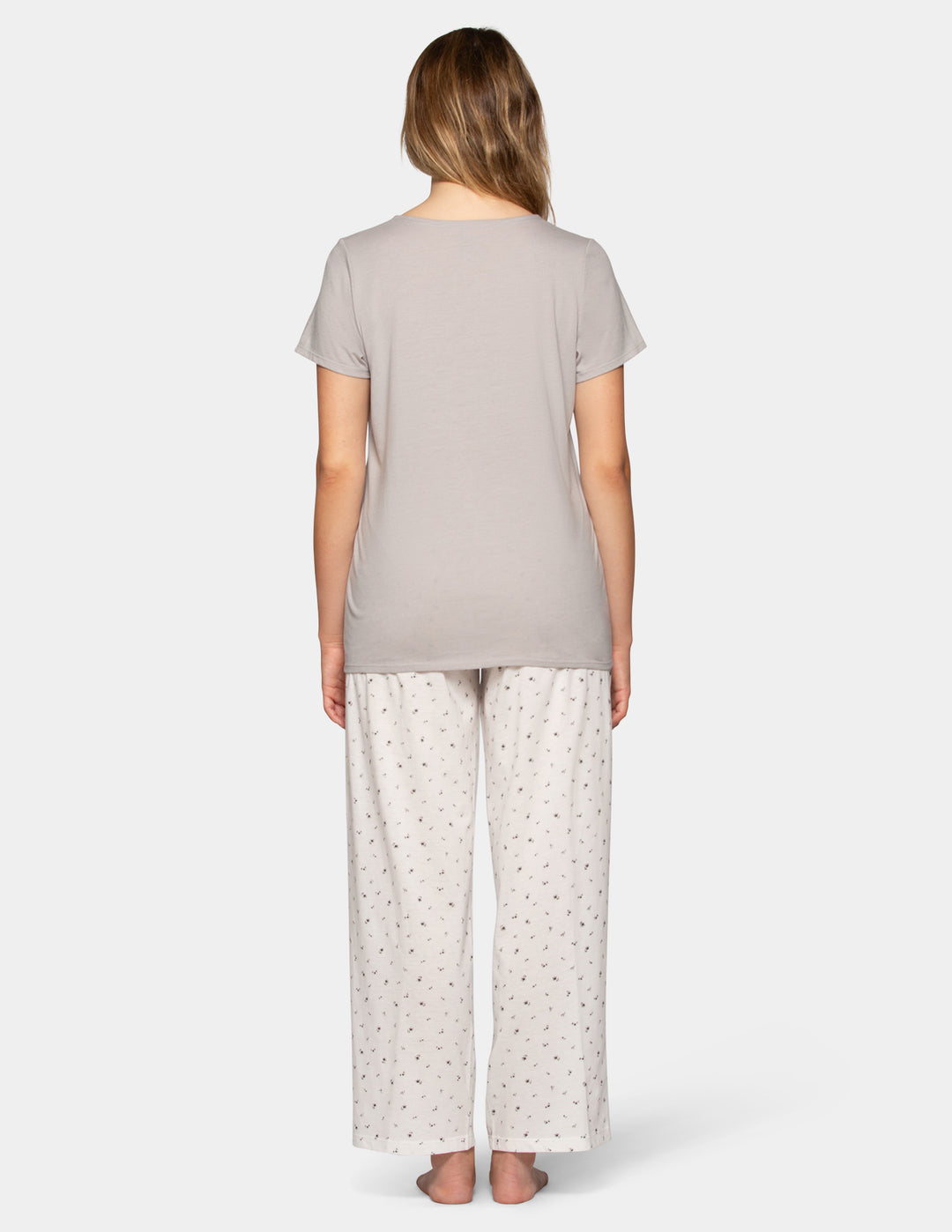 Woman wearing a grey pajama short sleeve tee and flower pattern pants set