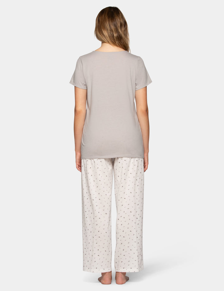 Woman wearing a grey pajama short sleeve tee and flower pattern pants set