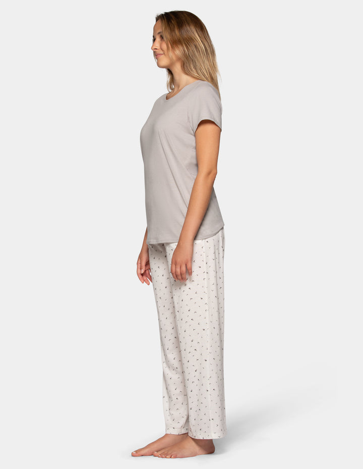 Woman wearing a grey pajama short sleeve tee and flower pattern pants set sideview