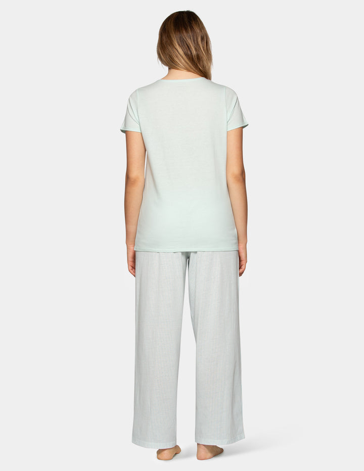 Woman wearing a pale blue pajama short sleeve tee and stripe pants set