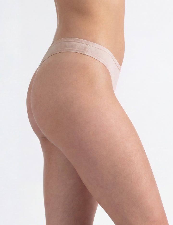 Woman wearing light pink thong underwear sideview