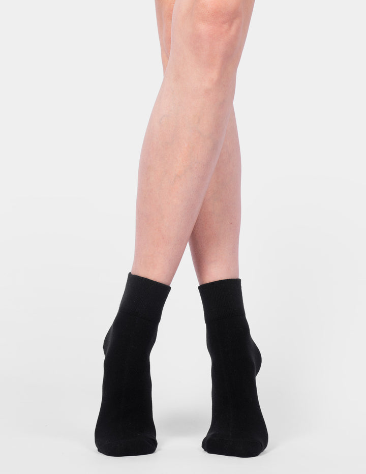 Black ankle socks worn by a person on a white background
