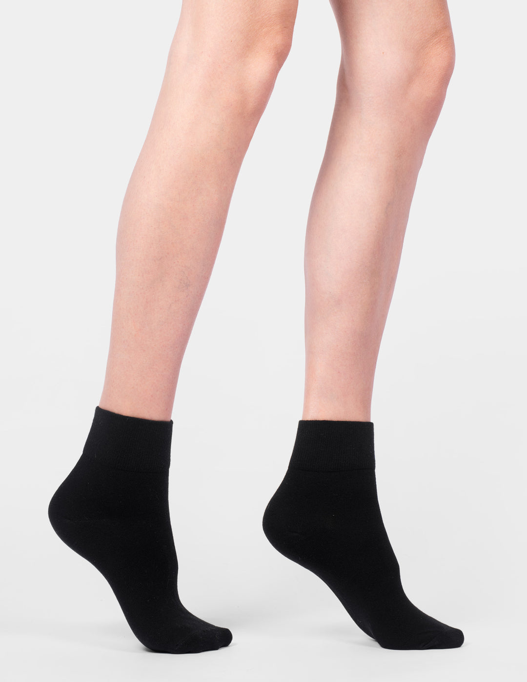 Black ankle socks worn by a person on a light gray background