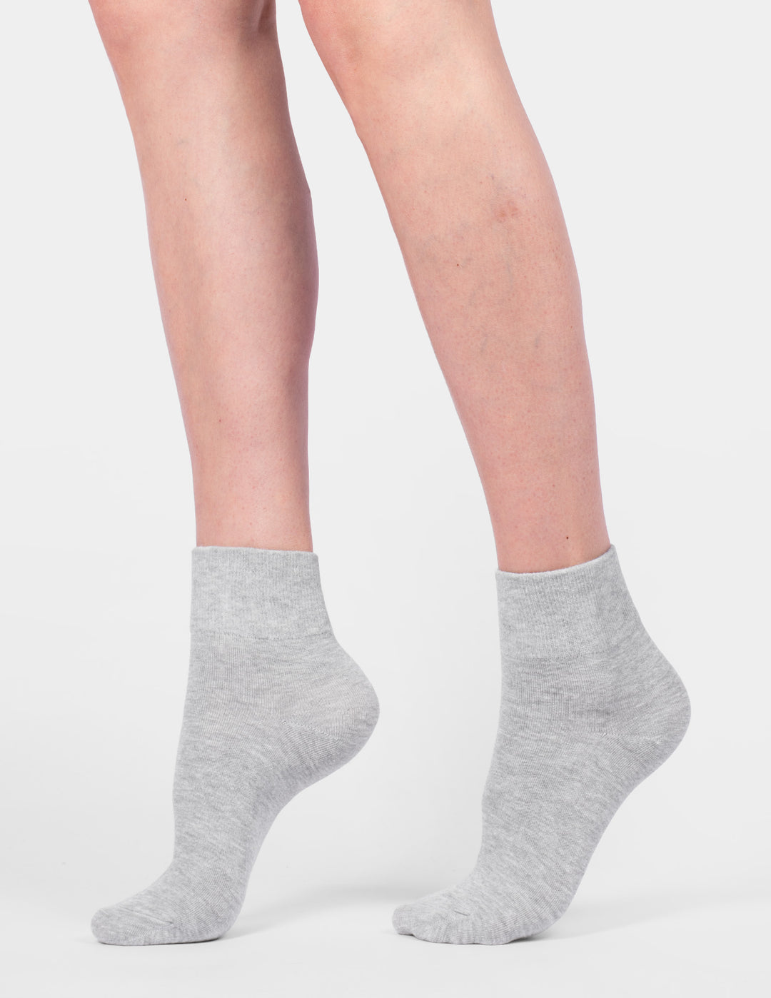 Gray ankle socks worn by a person on a light gray background