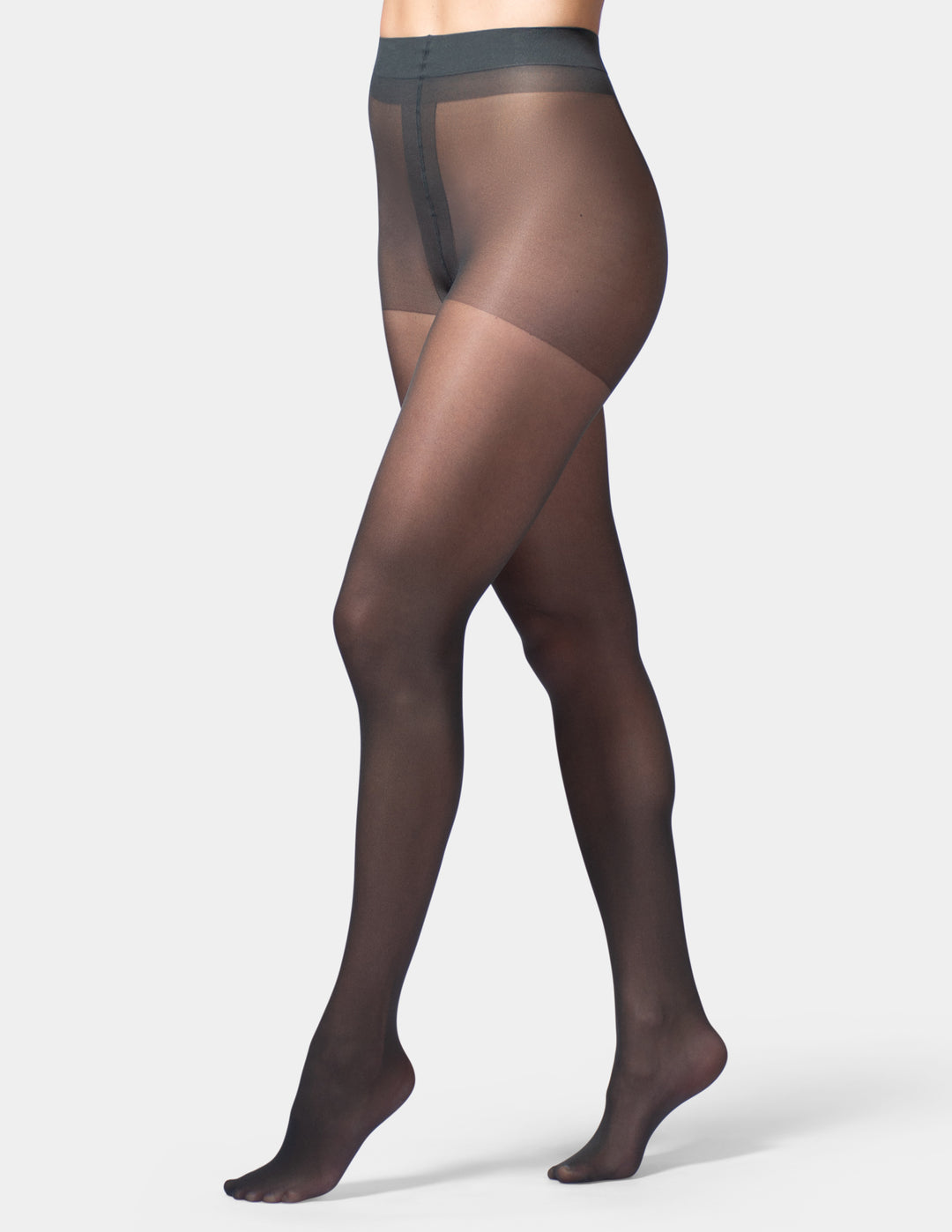 A model's legs wearing sheer black tights against a light gray studio background.