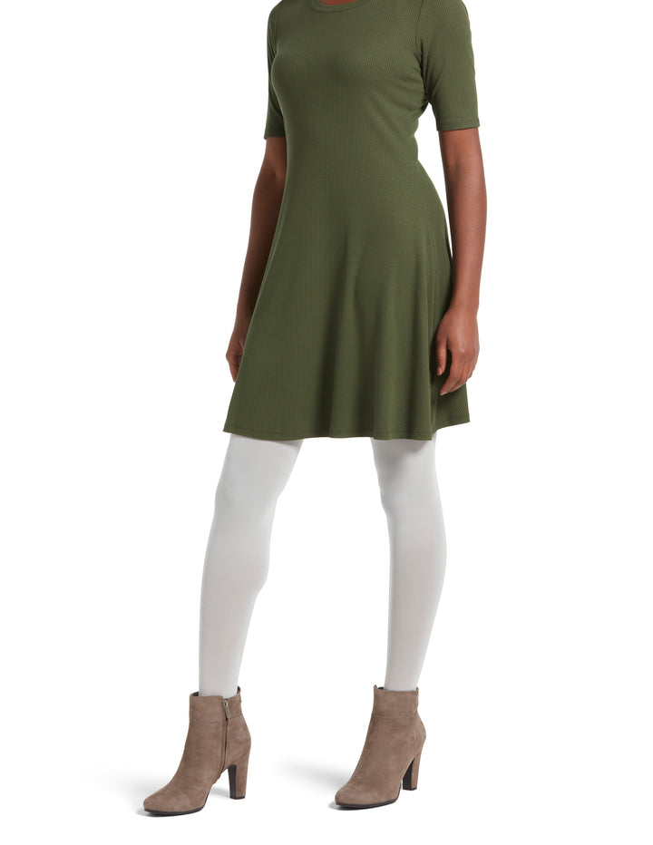 A person wearing sheer to waist white tights and a green knee-length dress with short sleeves. They are also wearing beige ankle boots.