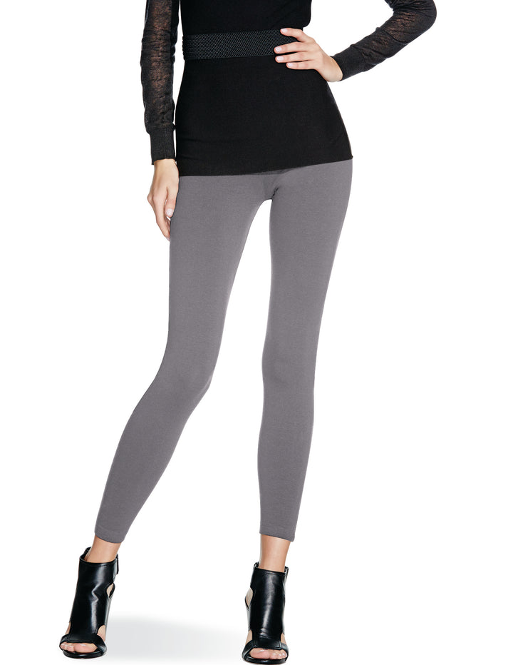 A pair of gray NO™ Seamless Leggings, showing the front view with the leggings worn by a model paired with a black top and black heels.