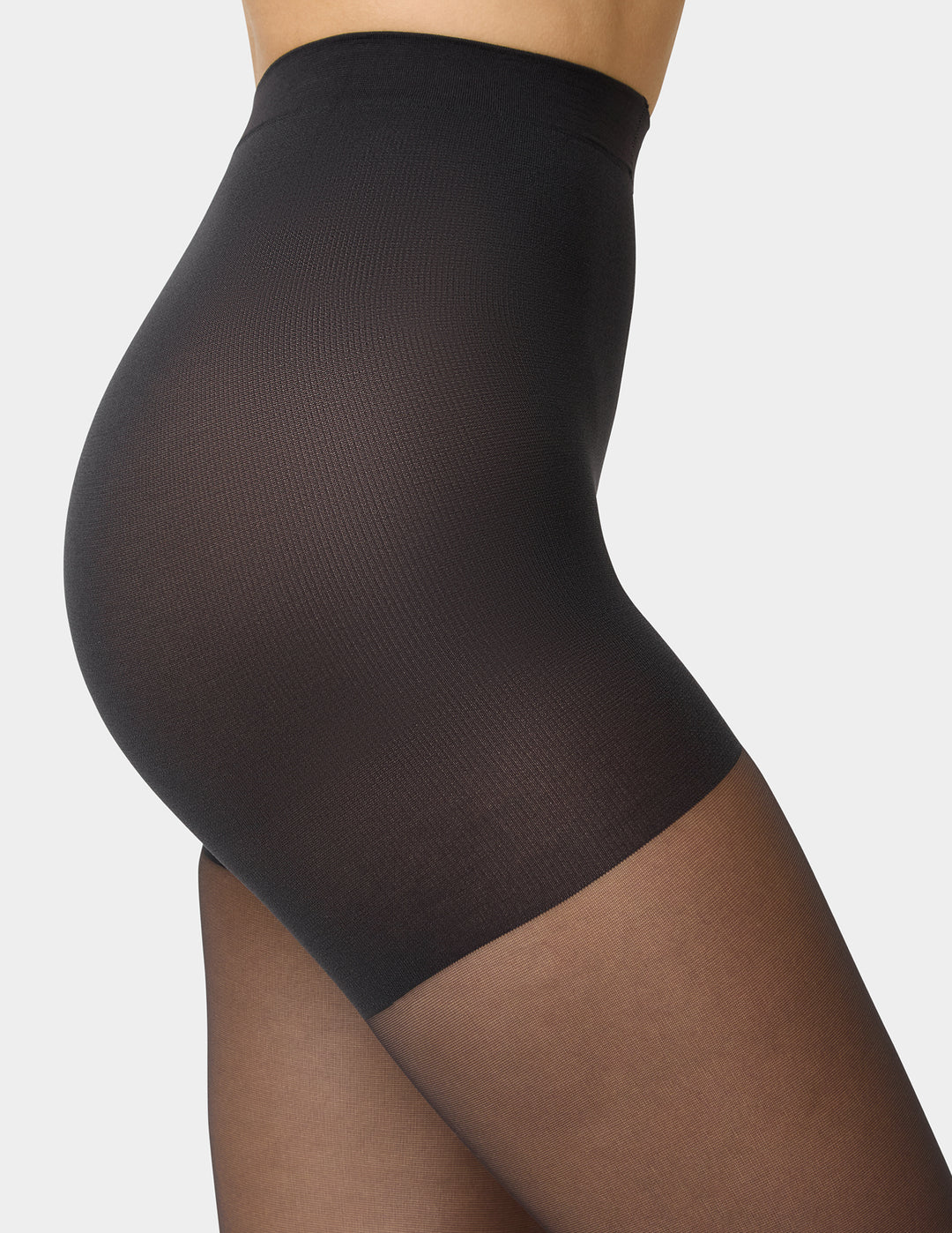 Close-up side view of a model wearing high-waisted black shapewear against a light gray studio background.