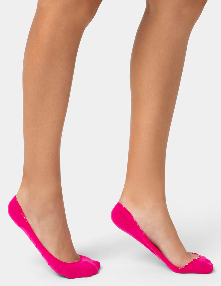 Person wearing bright pink socks on a white background
