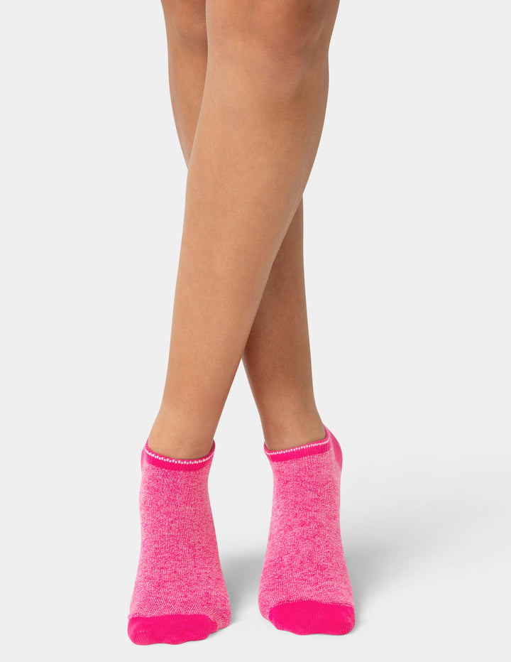 Person wearing bright pink socks on a white background