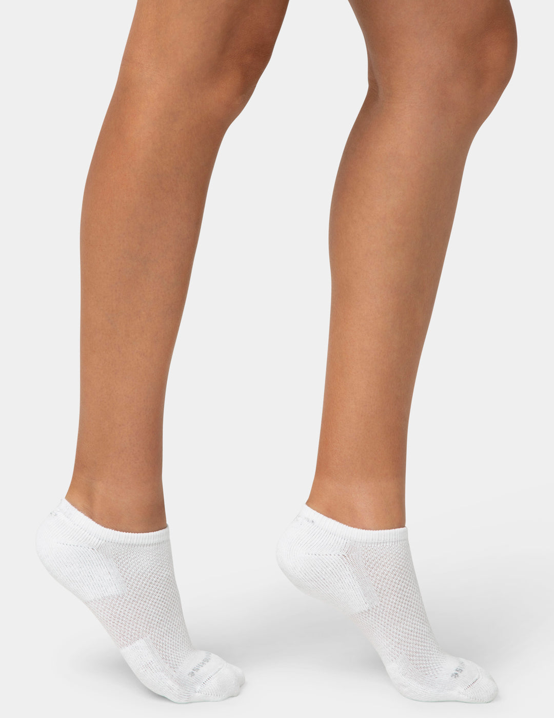 White ankle socks worn with beige skin on a light gray background