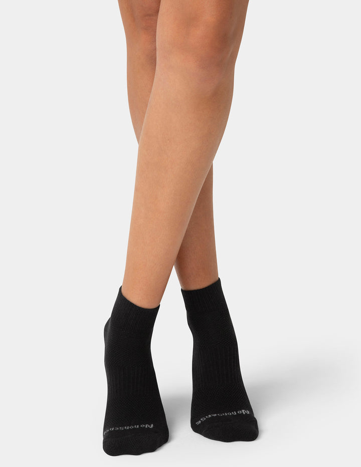Black ankle socks worn by a person on a white background