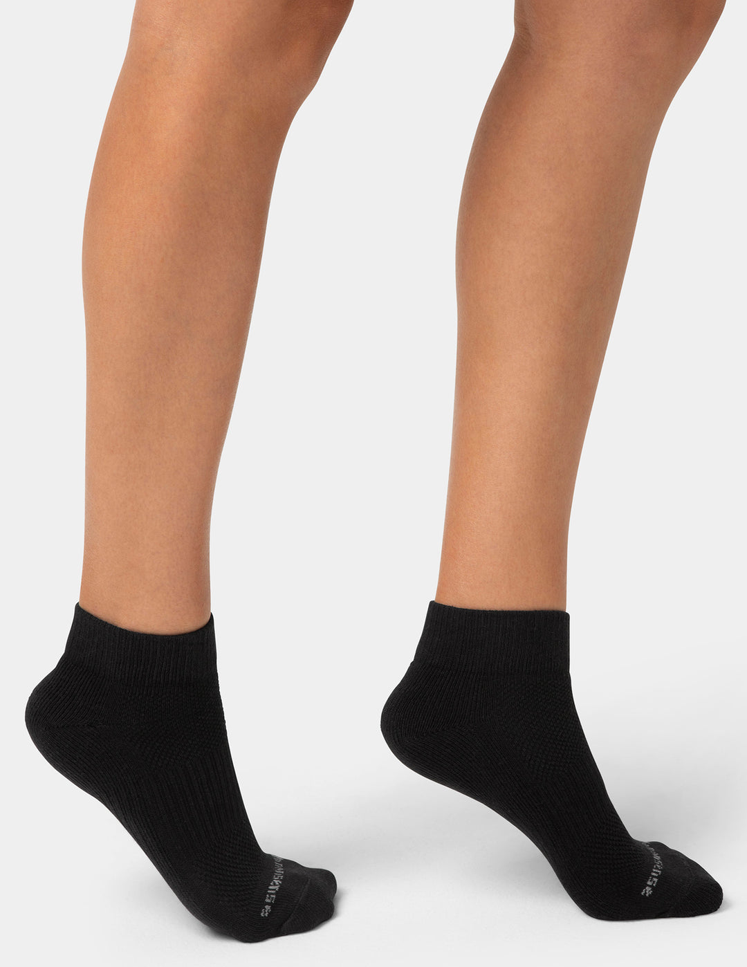 Black ankle socks worn by a person on a white background