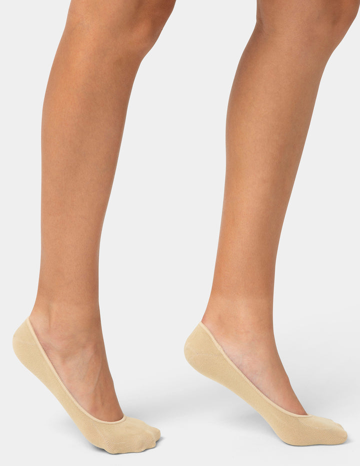 Beige no-show socks worn by a person on a light gray background