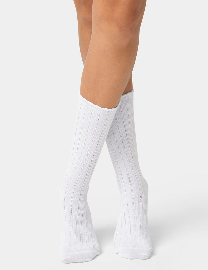 White knee-high socks worn by a person on a white background