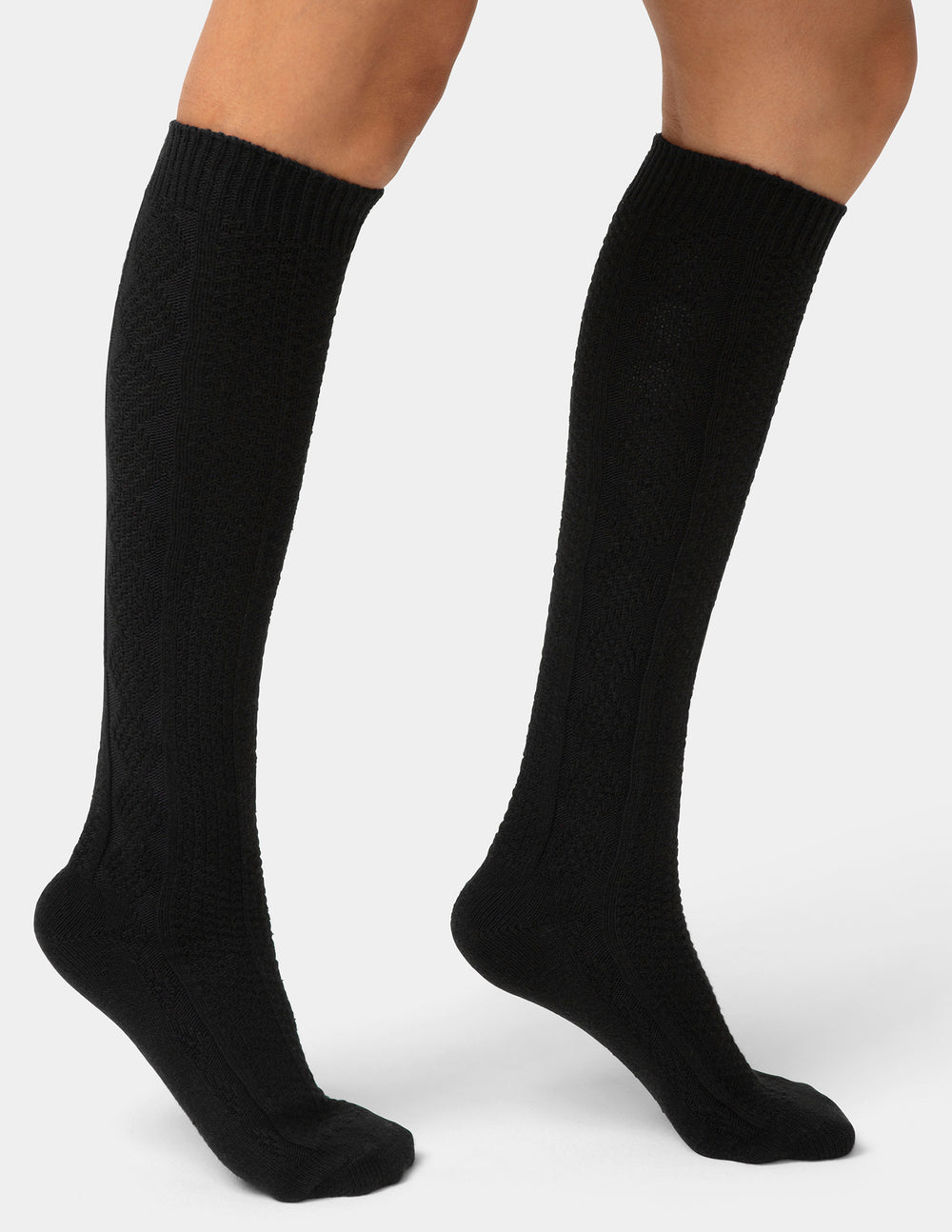 Black knee-high socks worn by a person on a white background