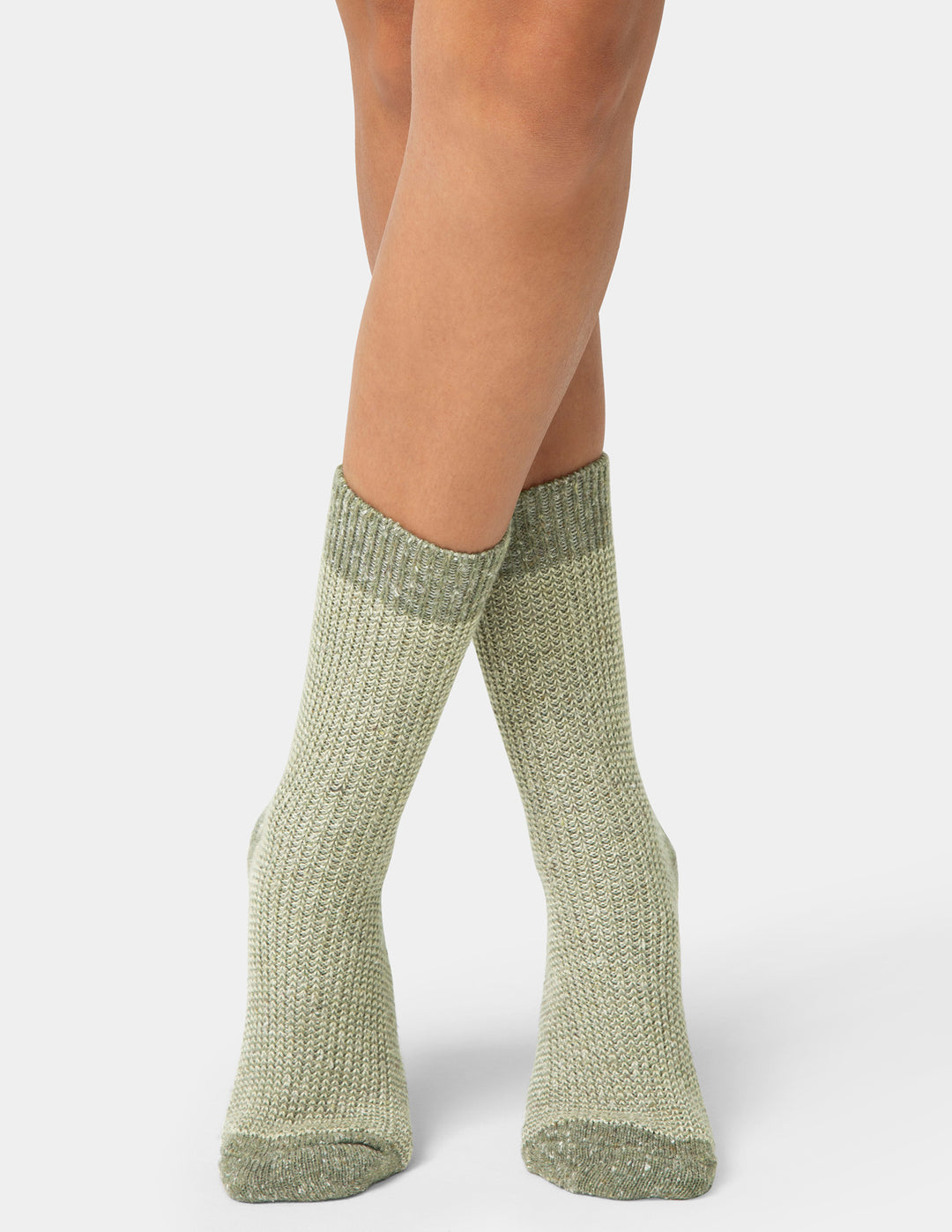 Green knitted socks worn by a person on a white background
