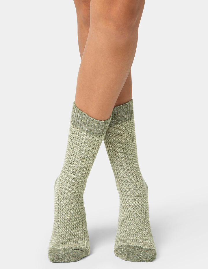 Green knitted socks worn by a person on a white background