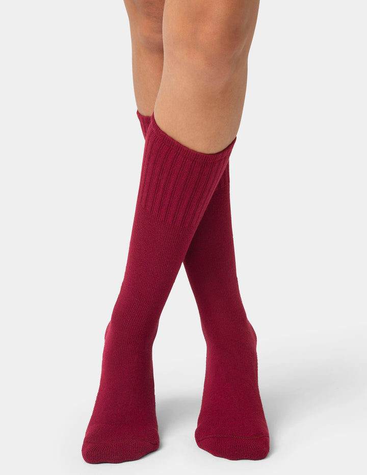 Red knee-high socks worn by a person on a white background