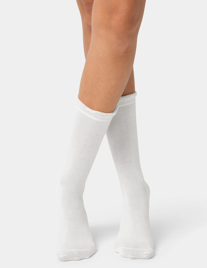 White ruffle edge crew socks worn by a person on a light gray background