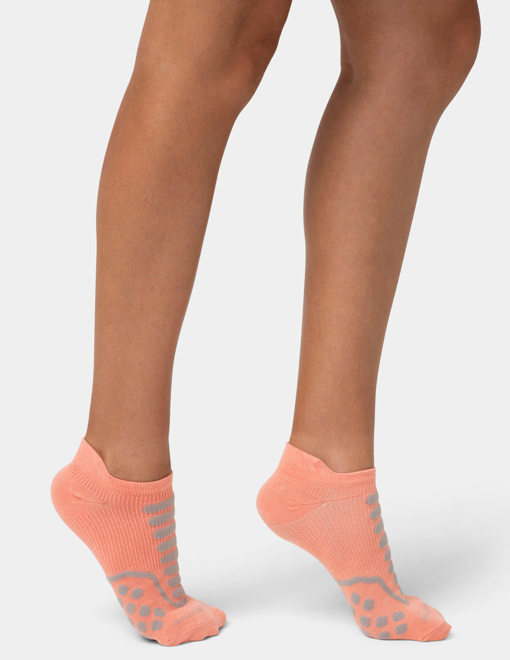 Person wearing coral ankle socks with gray accents on a white background