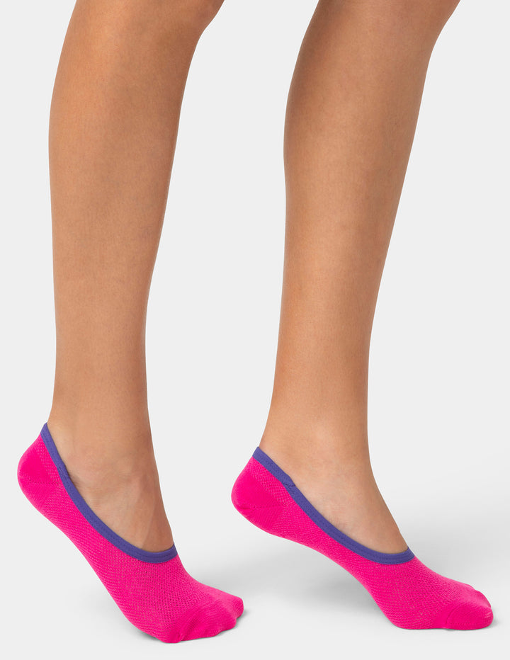 Pink socks with blue trim worn by a person on a white background