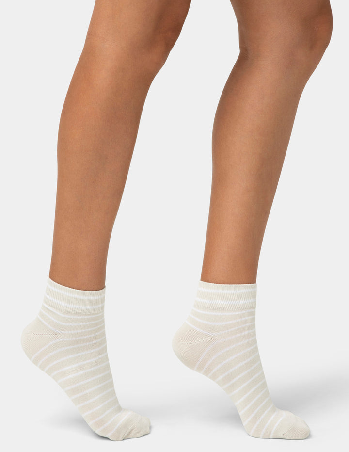 White striped socks worn by a person on a light gray background
