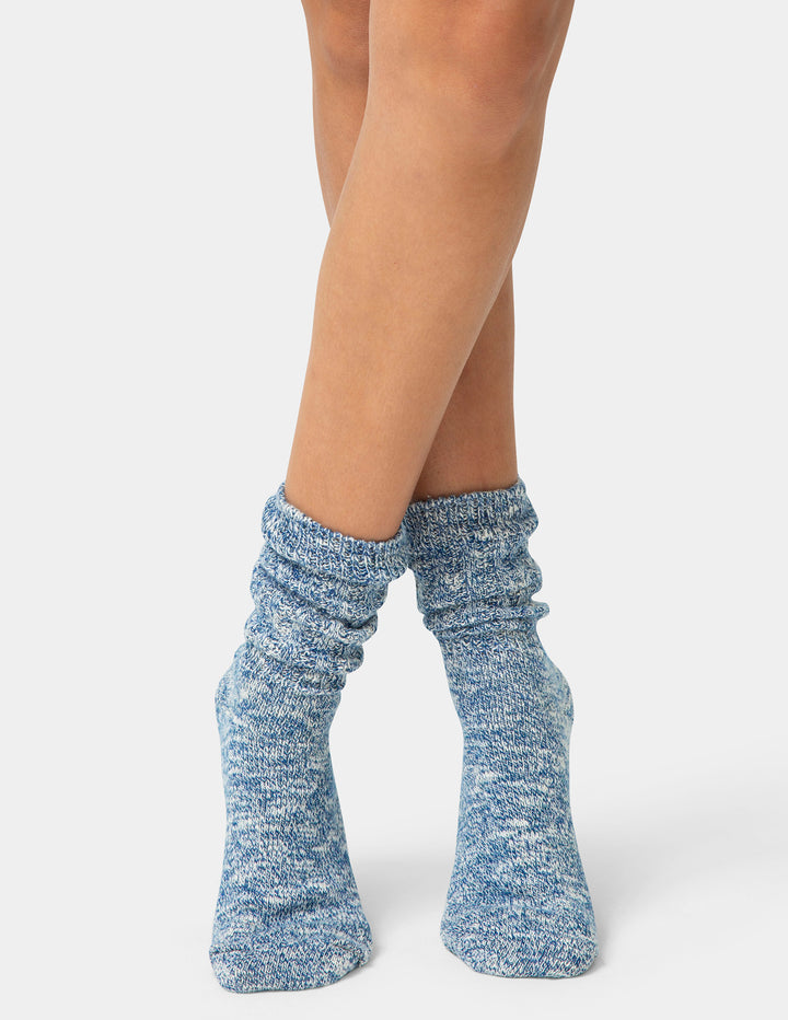 Blue knitted socks worn by a person on a white background