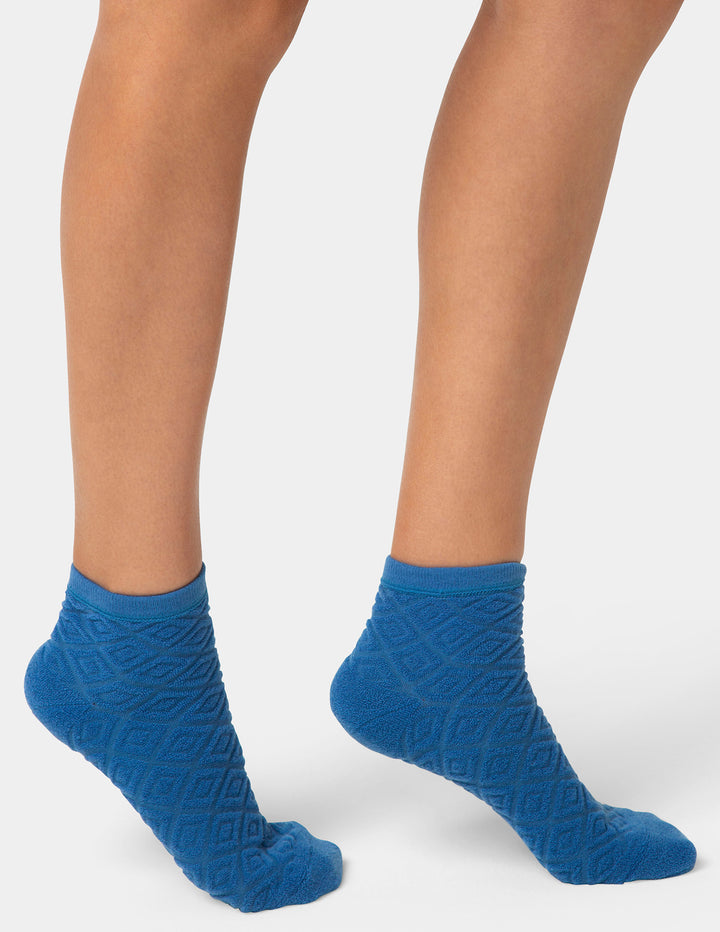 Blue textured socks worn by a person on a white background
