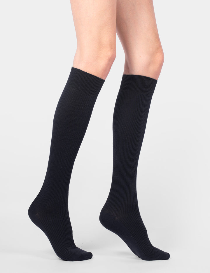 Black knee-high socks worn by a person on a light gray background