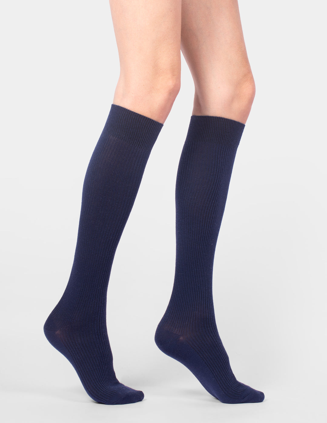 Navy blue knee-high socks worn by a person on a light gray background