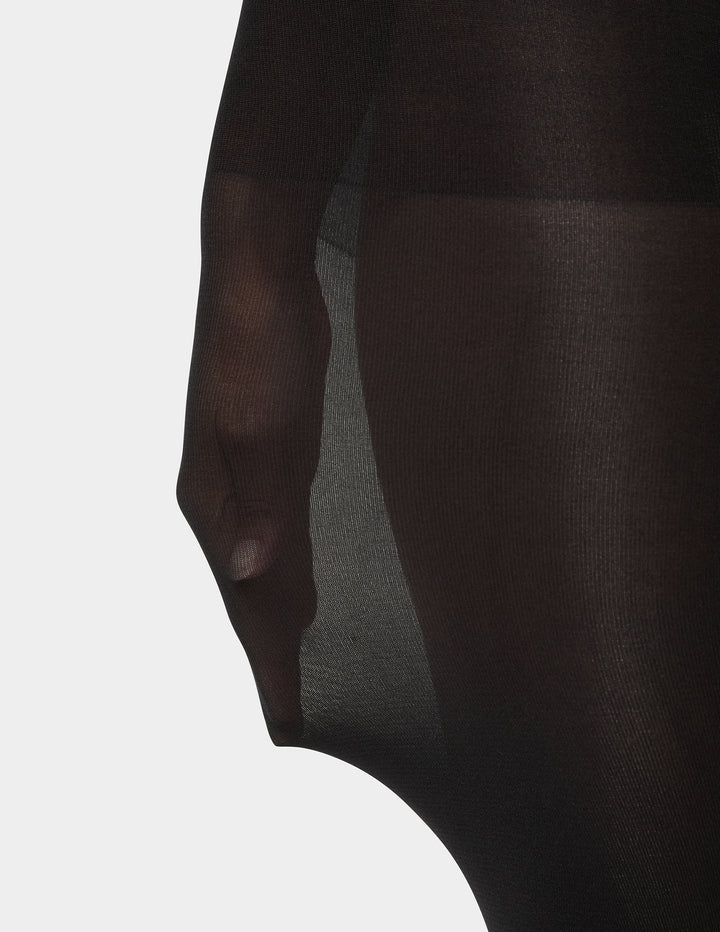 Close-up of a person wearing black tights showing stretch on a light background